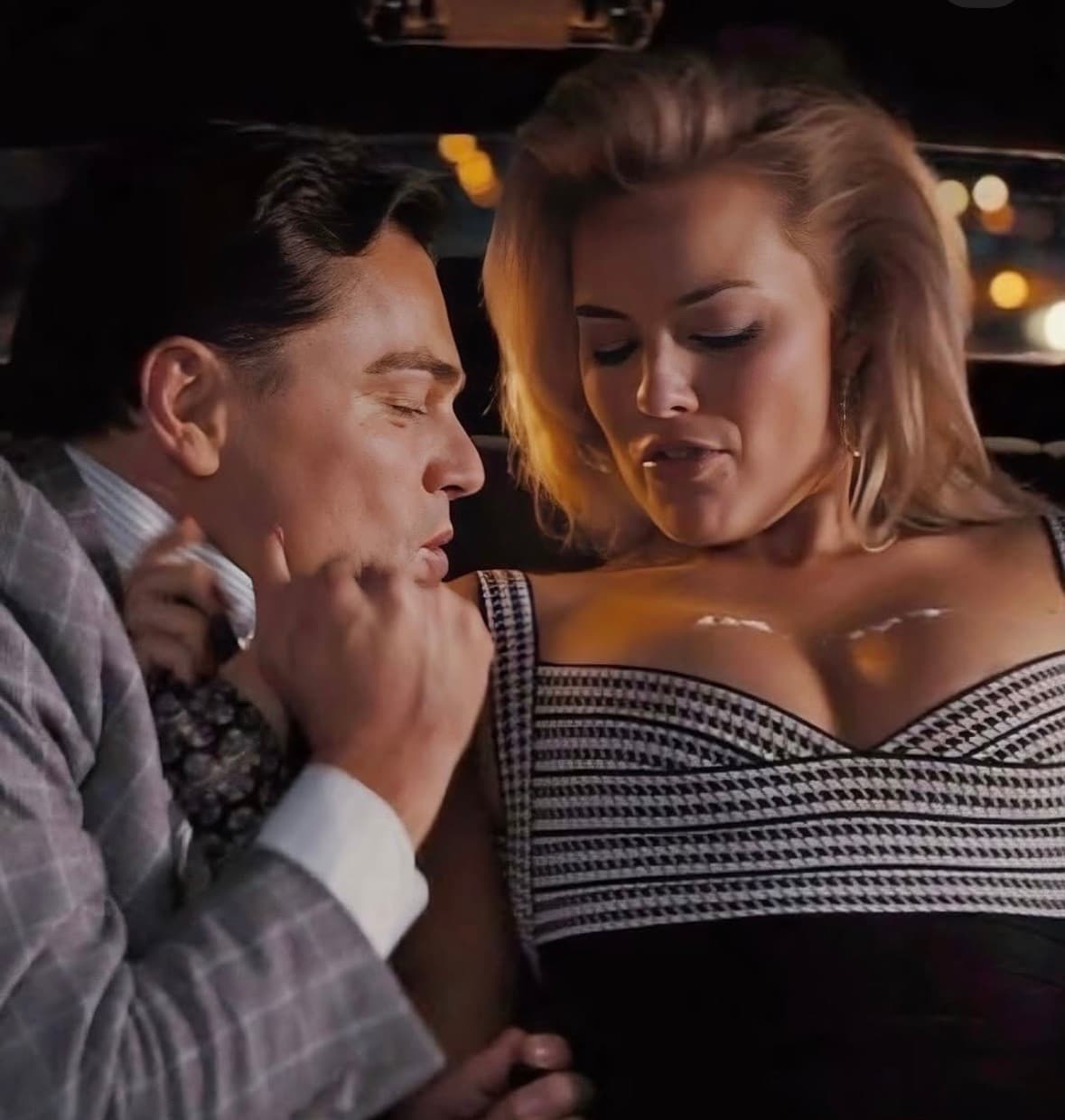 Leonardo DiCaprio schnupft weißes Pulver vom Dekolleté einer blonden Frau in einem dunklen Auto.